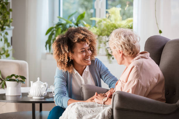 Royal Homecare aide talking to an older woman in a recliner